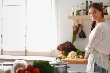 Mutfakta masanın yanında duran genç bir kadın.