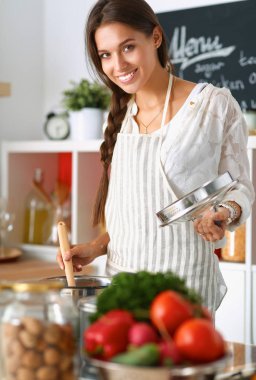 Mutfakta ahşap kaşıkla yemek pişiren kadın