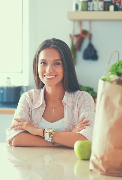 Mujer joven sentada cerca de escritorio en la cocina — Foto de Stock