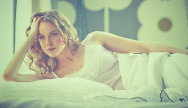 Güzel bir kadın yatağında uzanıyor.