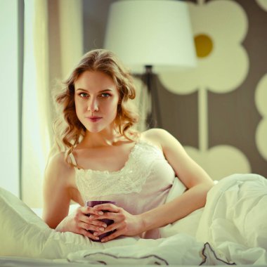 Genç kadın yatakta yatan ise kahve veya çay içme