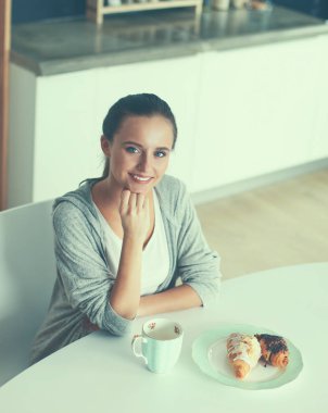 Mutfak masasında tatlı kruvasan ile çay içme kadın