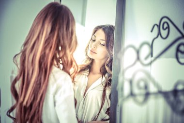 Genç kadın kendini evde aynada yansıma arıyor