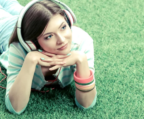 Mujer escuchando la música sentada en la hierba —  Fotos de Stock