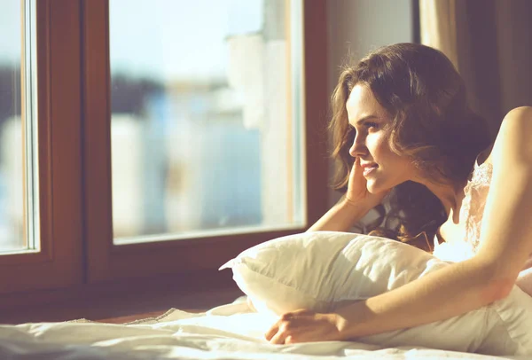 Nő az ágyban fekve, a kora reggeli órákban közelében ablak — Stock Fotó