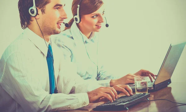 Jonge zakenvrouw en knappe zakenman in hoofdtelefoons met behulp van laptops terwijl u werkt in office — Stockfoto
