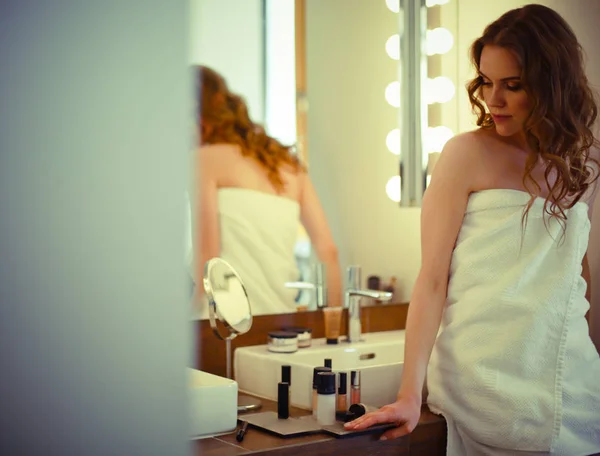 Jeune femme se regardant dans le miroir sur la salle de bain — Photo