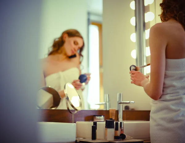 Jeune femme se regardant dans le miroir sur la salle de bain — Photo