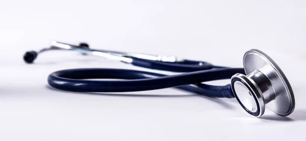 Medical stethoscope lying on cardiogram with pile — Stock Photo, Image