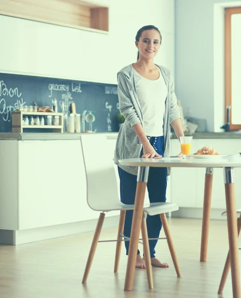 Ung kvinna med apelsinjuice och tablett i köket — Stockfoto