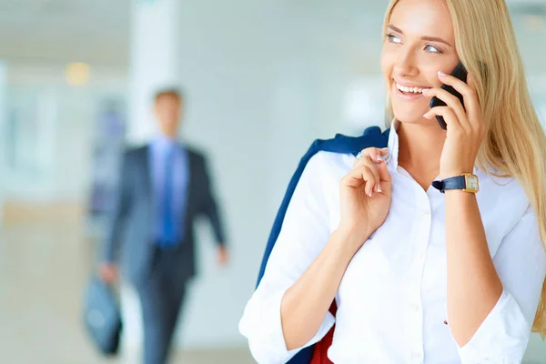 Zakenvrouw staat tegen kantoorraam te praten op mobiele telefoon — Stockfoto