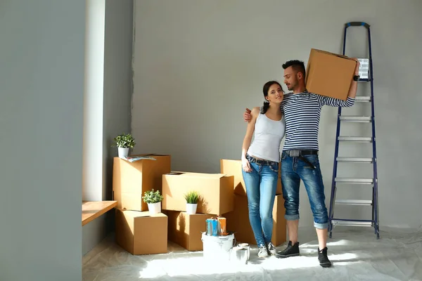 Felice giovane coppia disimballaggio o scatole di imballaggio e trasferirsi in una nuova casa — Foto Stock