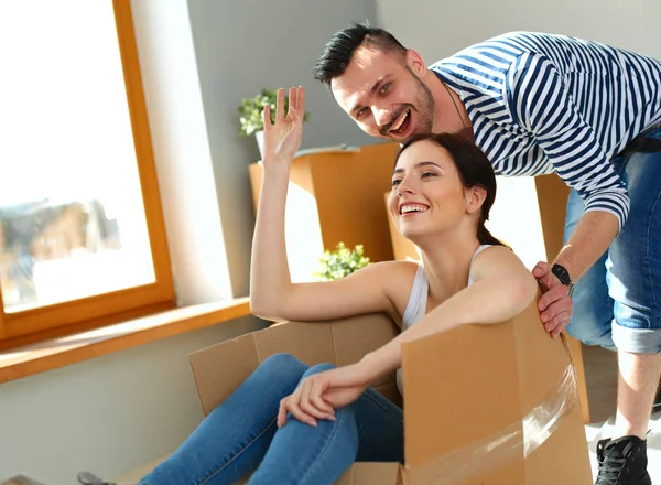 Feliz jovem casal desembalagem ou embalagem caixas e se mudar para uma nova casa — Fotografia de Stock