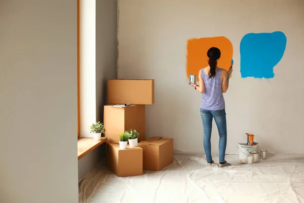 Gelukkig glimlachende vrouw schilderen interieur muur van nieuw huis — Stockfoto