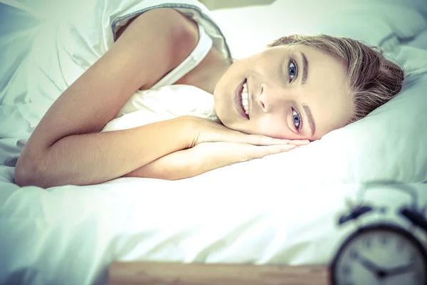 Jovem mulher dormindo e despertador no quarto em casa — Fotografia de Stock