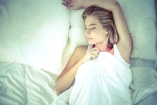 Молодая спящая женщина и будильник в спальне на дому — стоковое фото