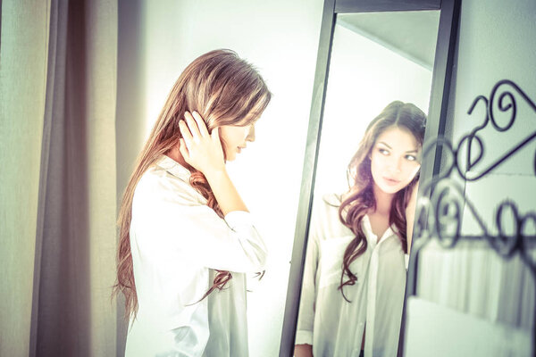 Молодая женщина смотрит на себя отражение в зеркале дома
