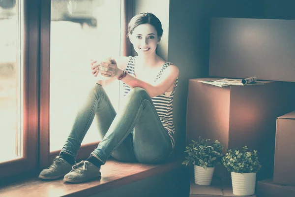 Girl sitting on windowsill at new home with cup — Stock Photo, Image