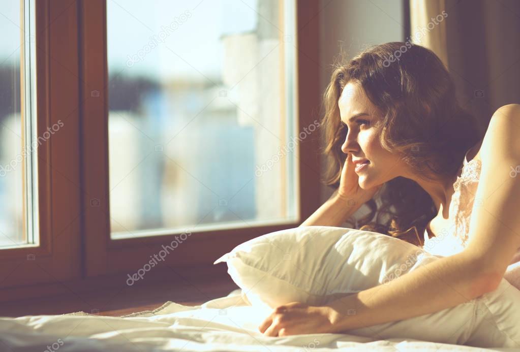 Woman lying in bed at early morning near window