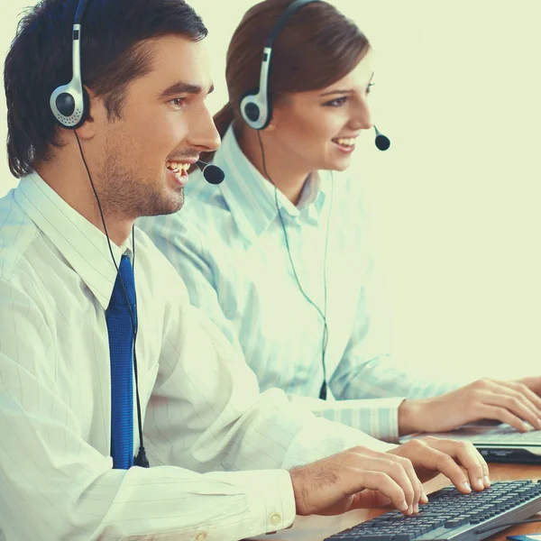 Young business woman and handsome businessman in headsets using laptops while working in office — Stock Photo, Image