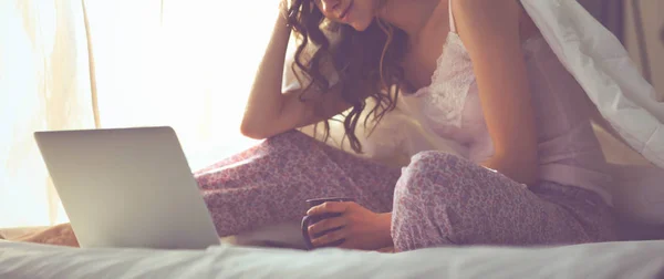 Fiatal gyönyörű nő ült az ágyban laptop — Stock Fotó