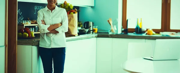 Retrato de jovem de pé com os braços cruzados contra o fundo da cozinha — Fotografia de Stock