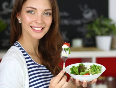 Salata yemek ve karışık salata tutan genç kadın