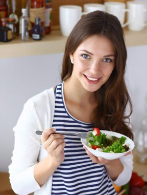 Salata yemek ve karışık salata tutan genç kadın