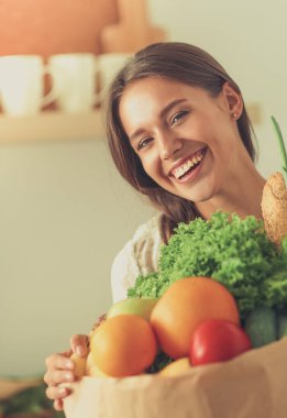 Elinde sebzeli alışveriş torbası tutan genç bir kadın.