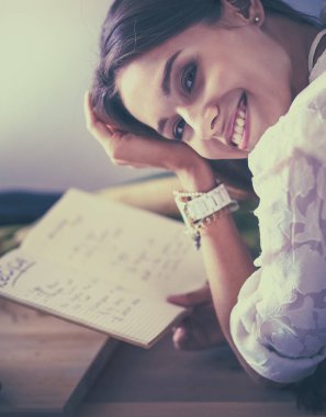 Mutfakta yemek kitabı okuyan genç bir kadın yemek tarifi arıyor.