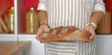 Genç bir kadın mutfağında lezzetli taze ekmek tutuyor.