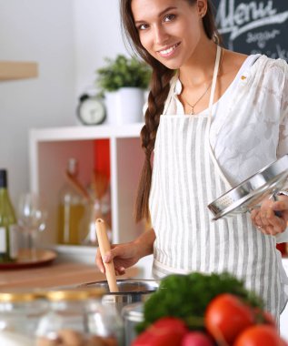Mutfakta ahşap kaşıkla yemek pişiren kadın