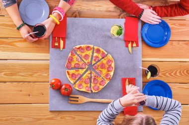 Bir grup genç insan pizza masada yemek.