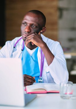 Masada dizüstü bilgisayarda çalışan genç bir Afrikalı doktor.