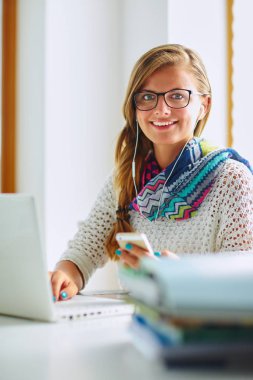 Kitapların arasında masa başında oturan genç bir kadın.