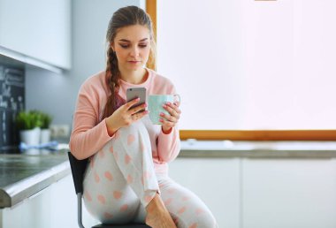 modern mutfakta otururken cep telefonu kullanan kadın