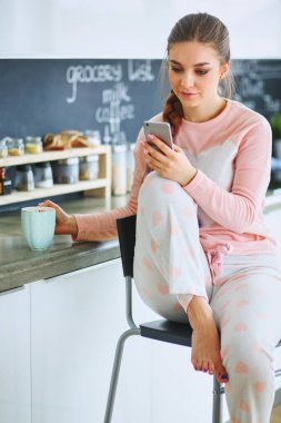 modern mutfakta otururken cep telefonu kullanan kadın