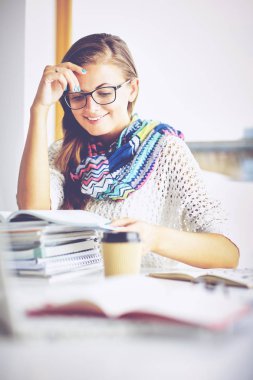 Kitapların arasında masa başında oturan genç bir kadın.