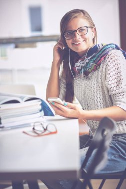 Kitapların arasında masa başında oturan genç bir kadın.