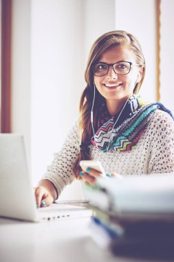 Kitapların arasında masa başında oturan genç bir kadın.