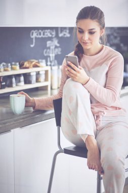 modern mutfakta otururken cep telefonu kullanan kadın