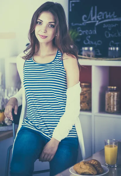 Retrato de uma mulher bonita sentada na cozinha — Fotografia de Stock