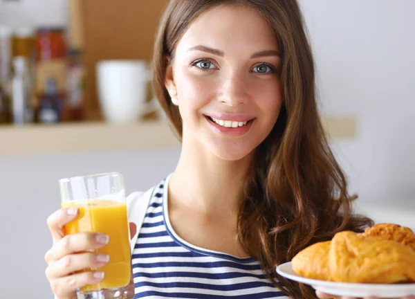 Ung kvinna med ett glas juice och kakor — Stockfoto