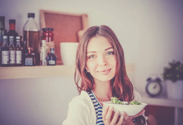 Νεαρή γυναίκα τρώει σαλάτα και κρατώντας μια ανάμικτη σαλάτα — Φωτογραφία Αρχείου