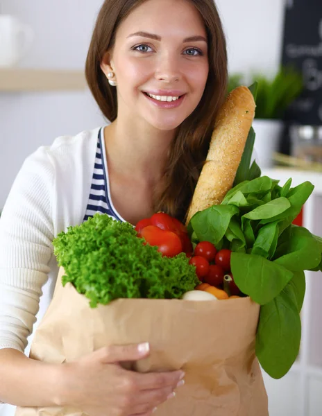 Ung kvinna som håller i matkassen med grönsaker — Stockfoto