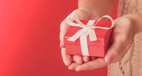 Kvinnlig hand innehav presentförpackning isolerad på röd bakgrund — Stockfoto