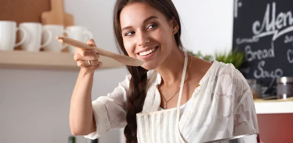 在厨房里用木勺做饭的女人 — 图库照片