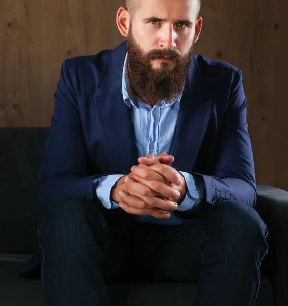 Businessman sitting the sofa in office lobby, isolated on dark background — Stock Photo, Image