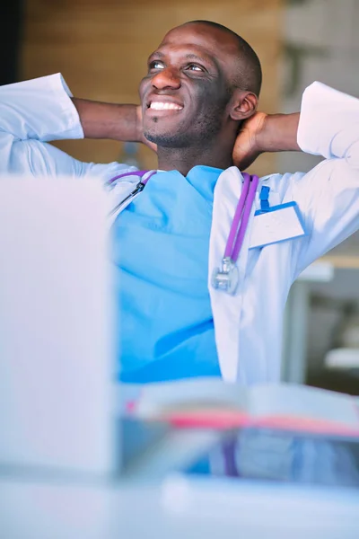 Jeune médecin africain travaillant sur ordinateur portable au bureau — Photo