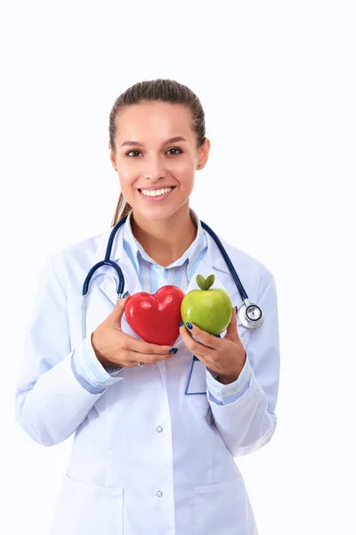 Bonita sorridente médico feminino segurando coração vermelho e maçã verde — Fotografia de Stock